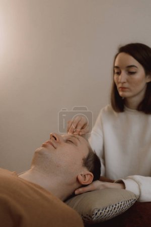 Massage énergétique pour homme relaxant et traitement de soins pour le corps et la santé mentale bras doux femme tenant la tête faisant barres d'accès et visage jeune procédure. Massage énergétique reprend la circulation de l'énergie dans le corps.