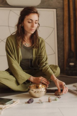 Photo for Woman playing on Tibetan singing bowl while sitting on yoga mat. Vintage tonned. Soft focus blurred and noise effect. - Royalty Free Image