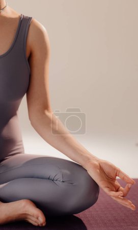 Foto de Vista frontal de cerca de una mujer haciendo yoga sentada en una esterilla de yoga. Mujer haciendo yoga sentada sobre un fondo claro - Imagen libre de derechos