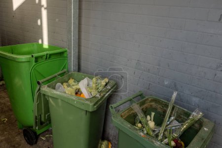Foto de Recipientes de basura con brócoli y verduras en envases de plástico cerca de una tienda de comestibles. - Imagen libre de derechos