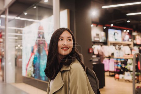 Foto de Hermosa chica adolescente sosteniendo bolsas de compras y sonriendo mientras hace compras en el centro comercial. - Imagen libre de derechos