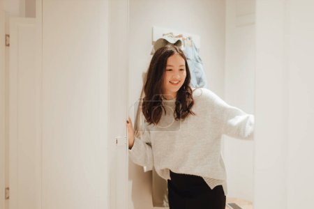 Foto de Adolescente coreana probando ropa nueva de moda en la cabaña en un centro comercial. Retail y consumismo. Promoción de venta y concepto de compras. Parte de una serie. - Imagen libre de derechos