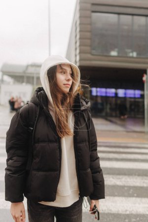 Tourist teenage girl traveling alone through the city streets in the autumn-winter season. Modern solo travel, lone traveler, Winter vacation railroad adventure concept.
