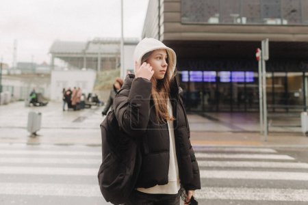 Tourist teenage girl traveling alone through the city streets in the autumn-winter season. Modern solo travel, lone traveler, Winter vacation railroad adventure concept.