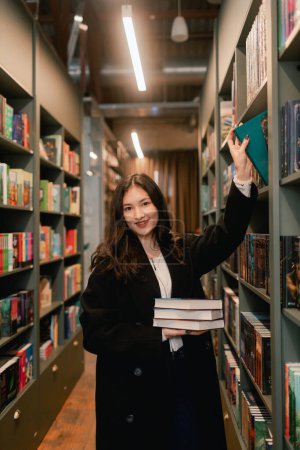 Foto de Pretty teen gen Z Chica estudiante coreana elige libro en una librería. Concepto de formación educativa. Parte de una serie. - Imagen libre de derechos