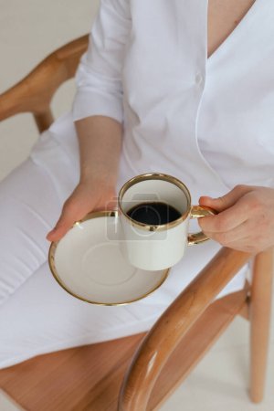 Foto de Concepto de medicina, salud y personas Primer plano médico gp femenino en uniforme blanco bebiendo té de café desayunando mientras trabajaba en la oficina de la clínica. Parte de una serie. - Imagen libre de derechos