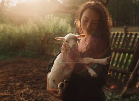 Veterinary woman holding sheep on livestock field for medical animal checkup. Happy, smile female vet doctor doing consultation on lamb on eco farm. Part of the series.