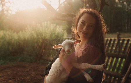 Mujer veterinaria sosteniendo ovejas en el campo de ganado para chequeo médico de animales. Feliz, sonríe doctora veterinaria haciendo consulta sobre cordero en eco granja. Parte de la serie.