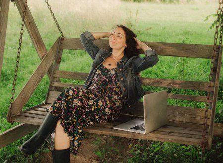 Mujer usando laptop en IT afuera en eco-granja. Charla en línea. Pase tiempo libre en la naturaleza. Concepto de trabajo desde casa, vida lenta, mantenerse conectado, distanciamiento social, internet. Parte de la serie.