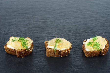 Foto de Piezas de pan con delicioso caviar de bacalao sobre fondo de pizarra de piedra negra - Imagen libre de derechos