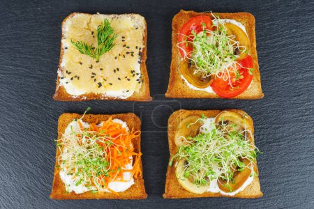 Foto de Piezas de pan con delicioso caviar de bacalao y verduras sobre fondo negro - Imagen libre de derechos