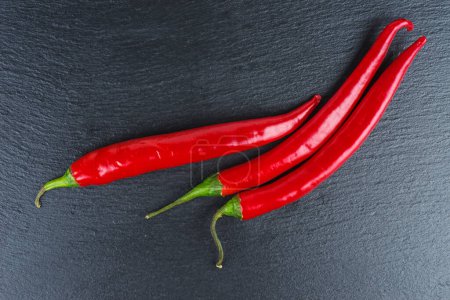 Photo for Fresh chili peppers on black stone slate background - Royalty Free Image