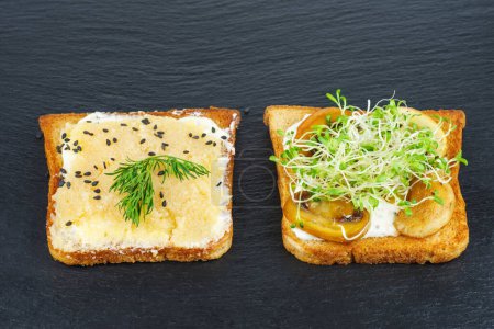 Foto de Piezas de pan con delicioso caviar de bacalao, champiñones a la parrilla y alfalfa germinada sobre fondo de pizarra de piedra negra - Imagen libre de derechos