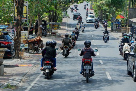 Foto de Ubud, Bali, Indonesia - 5 de septiembre de 2019: Motos y coches que conducen en una calle concurrida con tiendas de carretera de la popular ciudad turística - Imagen libre de derechos