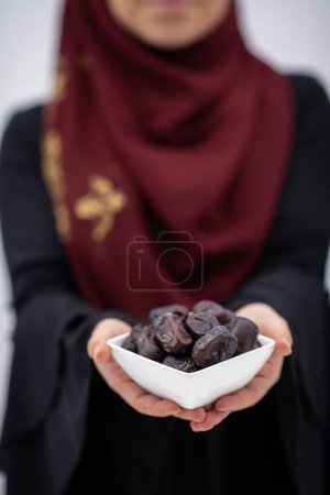 Foto de Mujer musulmana moderna sosteniendo un plato lleno de dátiles dulces en el tiempo iftar en ramadán kareem concepto de comida saludable islámica. Foto de alta calidad - Imagen libre de derechos