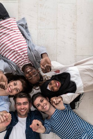 Top view of a diverse group of people lying on the floor symbolizes togetherness. High quality photo