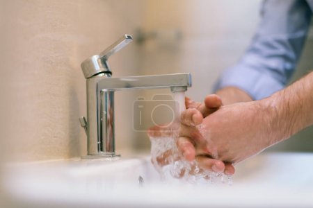 Photo pour Mna utiliser du savon et laver les mains sous le robinet d'eau. Concept d'hygiène détail des mains. Photo de haute qualité - image libre de droit