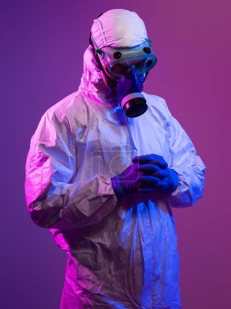Photo for Coronavirus covid-19 pandemic. Doctor scientist wearing protective biological suit and mask due to global healthcare epidemic warning and danger background in blue and pink neon lights background - Royalty Free Image