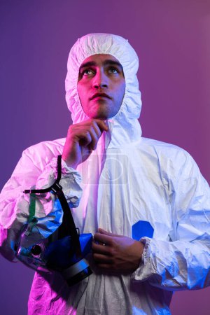 Photo for Coronavirus covid-19 pandemic. Doctor scientist wearing protective biological suit and mask due to global healthcare epidemic warning and danger background in blue and pink neon lights background - Royalty Free Image