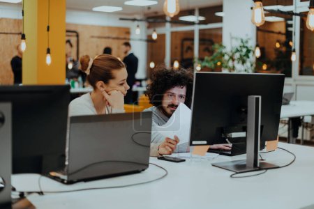 Two colleagues working on a project in modern startup offices. Guy with afro haircut and a female blonde employee working at the office. High quality photo