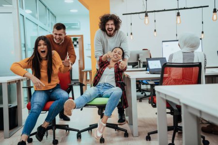 Photo for Team building and office fun. Young cheerful businesspeople in smart casual wear having fun while racing on office chairs and smiling - Royalty Free Image