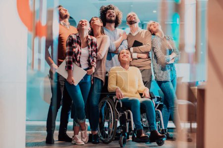 Businesswoman in a wheelchair on break in a modern office with her team in the background. High quality photo