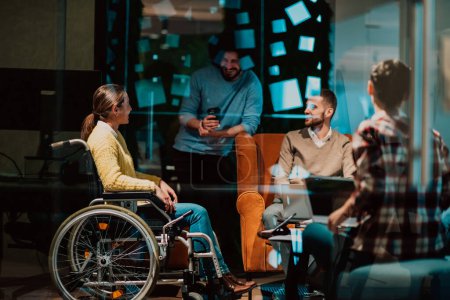 A businesswoman in a wheelchair having a business meeting with the team at a modern office. A group of young freelancers agree on new online business projects. 