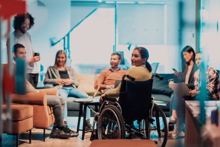 Eine Geschäftsfrau im Rollstuhl bei einem Geschäftstreffen mit dem Team in einem modernen Büro. Eine Gruppe junger Freiberufler einigt sich auf neue Online-Business-Projekte. 
