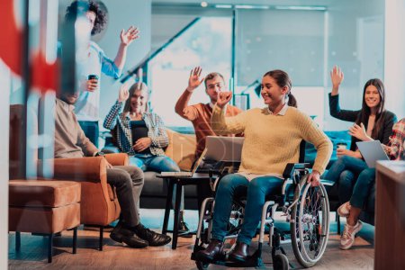 A businesswoman in a wheelchair having a business meeting with the team at a modern office. A group of young freelancers agree on new online business projects. 