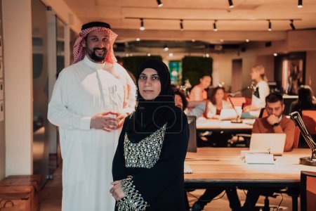 Foto de Foto de retrato del líder árabe hombre de negocios con la mujer musulmana hiyab discutiendo proyectos de negocios mientras usa tabletas y teléfonos inteligentes en una moderna oficina de vidrio. - Imagen libre de derechos