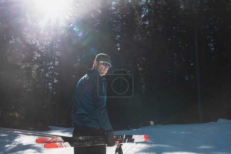 Photo for Portrait handsome male athlete with cross country skis in hands and goggles, training in snowy forest. Healthy winter lifestyle concept. High quality photo - Royalty Free Image