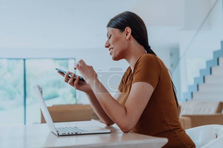 Photo for Woman sitting in living room using laptop and smartphone look at cam talk by video call with business friend relatives, head shot. Job interview answering questions - Royalty Free Image