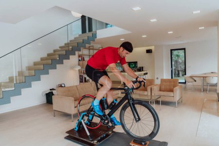 Photo for A man riding a triathlon bike on a machine simulation in a modern living room. Training during pandemic conditions - Royalty Free Image