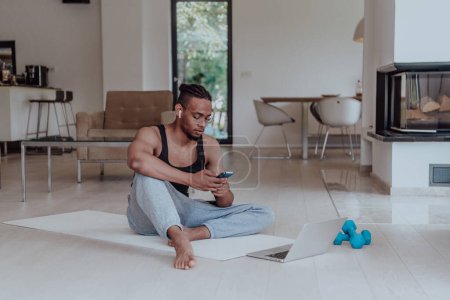 Photo for Training At Home. Sporty man doing training while watching online tutorial on laptop and using smartphone exercising in living room, free space - Royalty Free Image