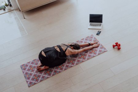 Foto de Joven hermosa mujer Ejercicio, estiramiento y práctica de yoga con entrenador a través de videoconferencia en Bright Sunny House. Vida Saludable, Bienestar y Concepto de Mindfulness. - Imagen libre de derechos