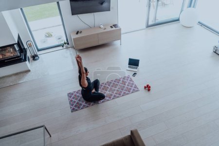 Photo for Young Beautiful Female Exercising, Stretching and Practising Yoga with Trainer via Video Call Conference in Bright Sunny House. Healthy Lifestyle, Wellbeing and Mindfulness Concept. - Royalty Free Image