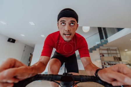 Téléchargez les photos : Un homme en vélo de triathlon sur une simulation de machine dans un salon moderne. Formation en cas de pandémie - en image libre de droit