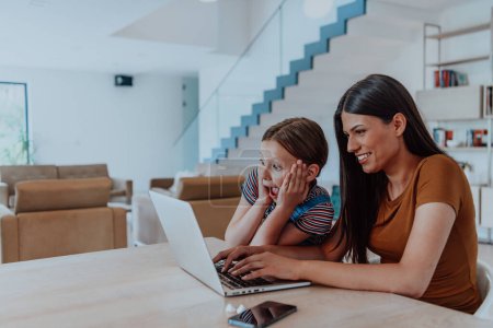 Photo for Mother with her daughter talking on laptop with family and friends while sitting in modern living room of big house. - Royalty Free Image