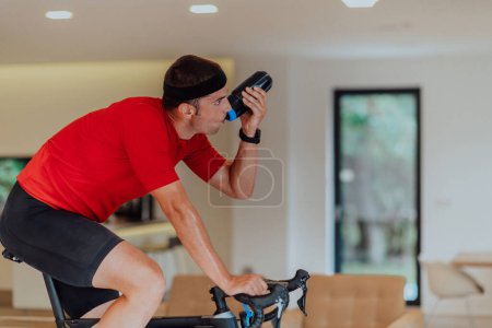 Foto de Un hombre montando una bicicleta de triatlón en una simulación de máquina en una sala de estar moderna. Entrenamiento en condiciones pandémicas - Imagen libre de derechos