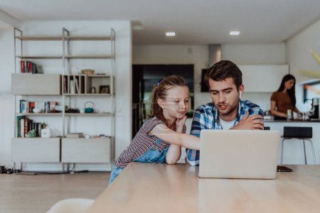 Téléchargez les photos : Père et fille dans la maison moderne parlent ensemble sur un ordinateur portable avec leur famille pendant les vacances. La vie d'une famille moderne. - en image libre de droit