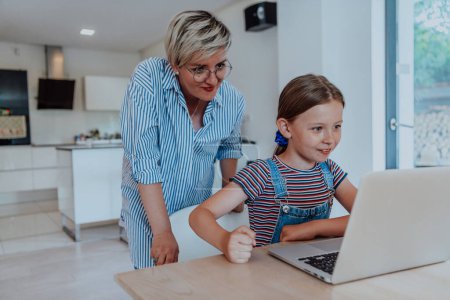 Photo for Mother with her daughter talking on laptop with family and friends while sitting in modern living room of big house. - Royalty Free Image