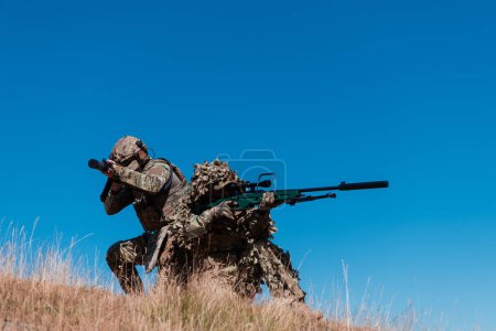 Photo for A sniper team squad of soldiers is going undercover. Sniper assistant and team leader walking and aiming in nature with yellow grass and blue sky. Tactical camouflage uniform - Royalty Free Image