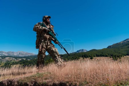 Foto de Soldado del ejército sosteniendo un rifle de francotirador con mira y caminando por el bosque. guerra, ejército, tecnología y concepto de personas - Imagen libre de derechos