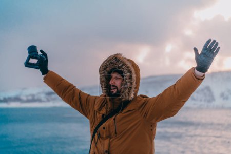 Foto de Un fotógrafo en las frías regiones de Skavdinava intenta tomar una foto para el periodismo en una fuerte tormenta de invierno. - Imagen libre de derechos
