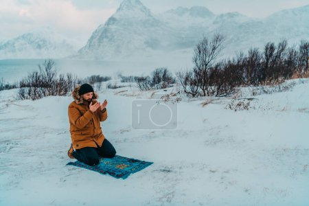 Foto de Un musulmán que viaja a través de las regiones árticas frías mientras realiza la oración musulmana namaz durante los descansos. - Imagen libre de derechos