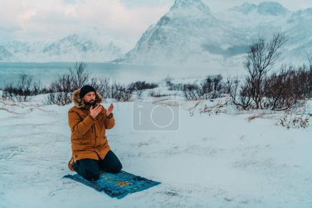 Téléchargez les photos : Un musulman voyageant à travers les régions froides arctiques tout en effectuant la prière musulmane namaz pendant les pauses. - en image libre de droit