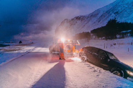 Photo for The roadside assistance service pulling the car out of the canal. An incident on a frozen Scandinavian road - Royalty Free Image
