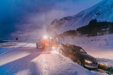 Foto de El servicio de asistencia en carretera sacando el coche del canal. Un incidente en una carretera escandinava congelada - Imagen libre de derechos
