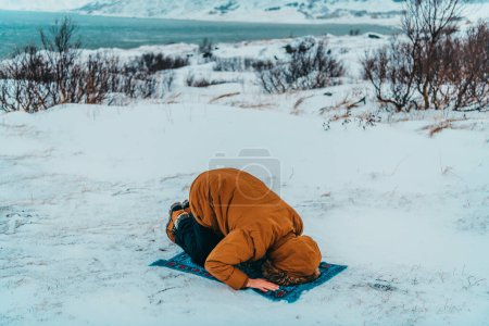 Foto de Un musulmán que viaja a través de las regiones árticas frías mientras realiza la oración musulmana namaz durante los descansos. - Imagen libre de derechos