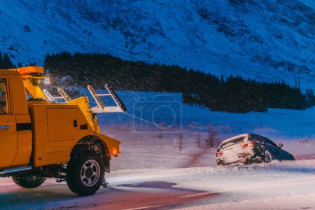 Photo for The roadside assistance service pulling the car out of the canal. An incident on a frozen Scandinavian road - Royalty Free Image